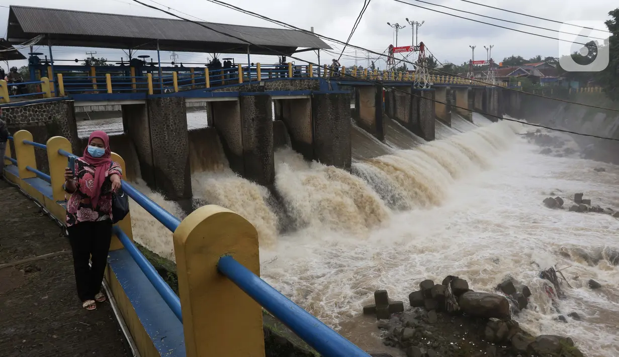 Warga berswafoto di Bendung Katulampa, Bogor, Jawa Barat, Jumat (19/2/2021). Meski sempat mengalami kenaikan debit air pada Jumat (19/2) pagi, namum sekitar pukul 15.00 WIB, debit air di Bendung Katulampa berada di zona hijau dengan ketinggian sekitar 50 cm. (Liputan6.com/Helmi Fithriansyah)