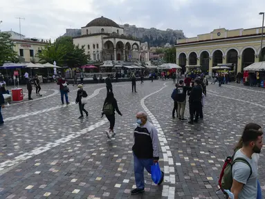 Pejalan kaki, beberapa mengenakan masker, berjalan di Monastiraki square, Athena, Selasa (9/11/2021). Yunani melaporkan rekor tertinggi baru kasus COVID-19 harian pada Senin ketika janji vaksinasi melonjak setelah pembatasan baru untuk warga yang tidak divaksinasi dimulai (AP Photo/Michael Varaklas)