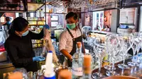 Bartender Gagan (kanan) dan seorang pelayan membersihkan bar jelang pembukaan kembali di New Delhi, 8 September 2020. Setelah sebelumnya ditutup karena pandemi COVID-19, mulai 9 September 2020 New Delhi mengizinkan bar kembali buka dengan kapasitas tempat duduk 50 persen. (Prakash SINGH/AFP)