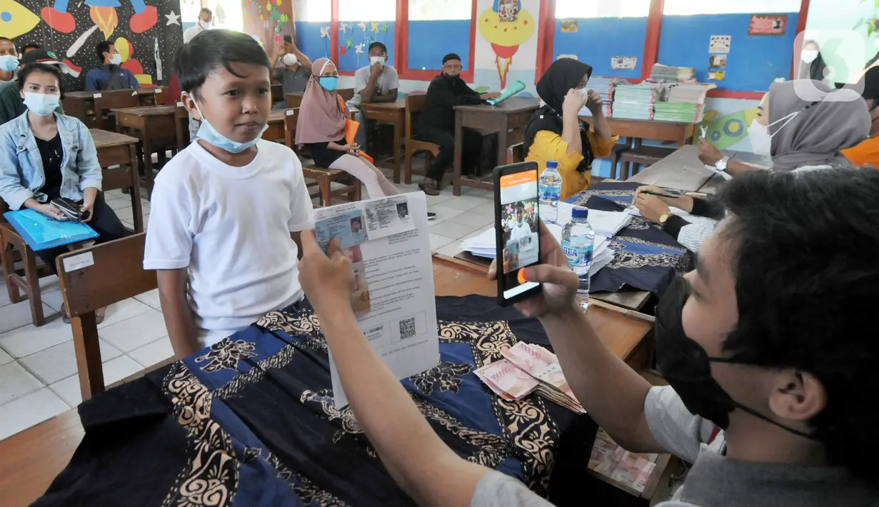 Petugas memotret warga penerima Bantuan Sosial Tunai (BST) di SDN Pondok Cabe Udik 03, Tangerang Selatan, Rabu (28/07/2021). Lebih dari dari 1800 warga mendapatkan BST yang dirapel dua bulan sekaligus dengan total Rp600ribu. (merdeka.com/Arie Basuki)