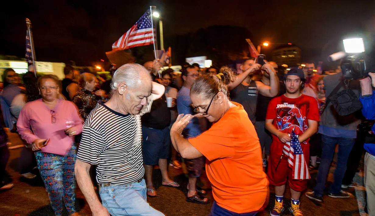 Warga Kuba menari saat merayakan wafatnya Fidel Castro di Miami, AS (26/11). Wafatnya pemimpin revolusi komunis Kuba tidak ditanggapi dengan kesedihan oleh warga Kuba yang menetap di Miami. (REUTERS/Gaston De Cardenas)