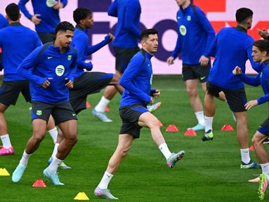 Penyerang Barcelona asal Polandia, Robert Lewandowski (tengah) melakukan pemanasan bersama rekan-rekan setimnya saat sesi latihan di Stadion Signal Iduna Park, Dortmund, Jerman pada 14 April 2025. (Ina FASSBENDER/AFP)