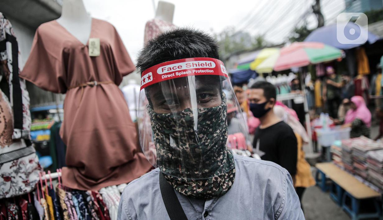 Pedagang menggunakan alat pelindung wajah (Face Shield) saat berjualan di Kawasan Tanah Abang, Jakarta, Senin (18/5/2020). Penggunaan alat pelindung wajah itu sebagai upaya untuk melindungi diri saat berhubungan dengan pembeli dalam pecegahan penyebaran COVID-19. (Liputan6.com/Faizal Fanani)