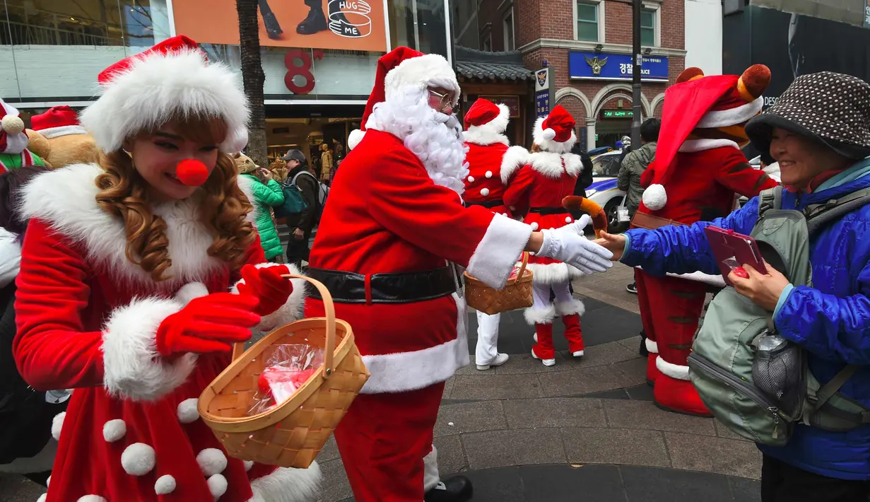 Santa Claus bersalaman dengan  seorang wanita saat mempromosikan musim Natal di distrik perbelanjaa,  Seoul (13/11). Meski sebagian besar penduduknya adalah umat Budha, anak muda Korsel menikmati perayaan musim Natal tersebut. (AFP Photo/Jung Yeon-Je)