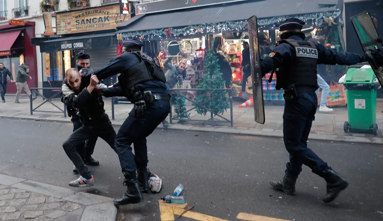 Seorang anggota komunitas Kurdi bentrok dengan petugas polisi di TKP tempat terjadinya penembakan di Paris, Prancis, 23 Desember 2022. Demonstrasi terjadi sebagai bentuk protes usai seorang pria berusia 69 tahun menembaki sekelompok orang di pusat kebudayaan suku Kurdi di Prancis. (AP Photo/Lewis Joly)