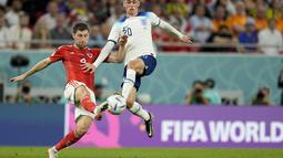 Pemain Inggris, Phil Foden (kanan) berebut bola dengan pemain Wales,&nbsp;Ben Davies saat matchday ketiga Grup B Piala Dunia 2022 di Ahmad Bin Ali Stadium, Rabu (30/11/2022). (AP/Abbie Parr)