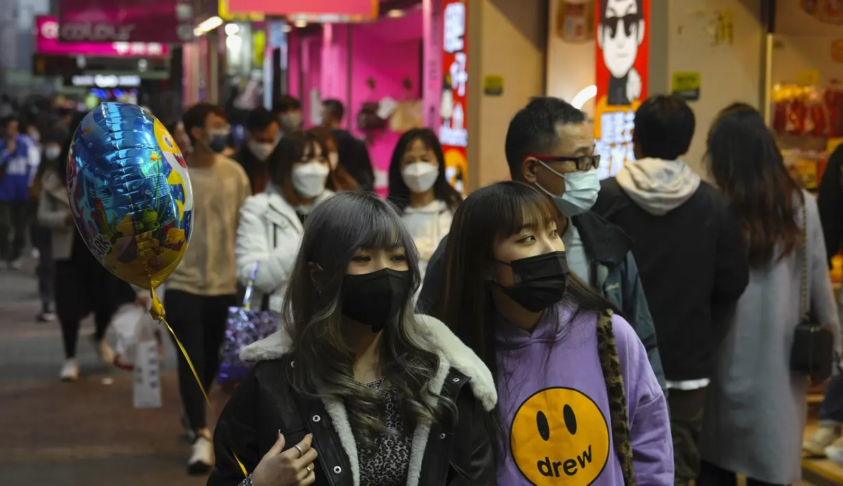 Orang-orang memakai masker untuk melindungi diri dari penyebaran virus corona, berjalan di jalan di Hong Kong (14/1/2022). Hong Kong akan menangguhkan penerbangan transit dari sekitar 150 negara dan wilayah yang dianggap berisiko tinggi karena virus corona selama sebulan penuh. (AP Photo/Kin Cheung)