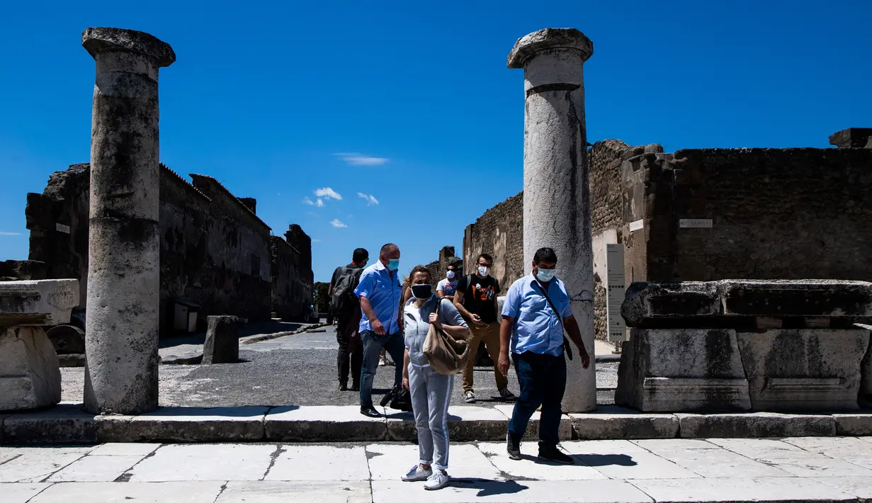 Orang-orang dengan mengenakan masker mengunjungi situs arkeologi Pompeii seusai kebijakan lockdown untuk mengendalikan penyebaran Covid-19 di Italia, Selasa (26/5/2020). Salah satu situs arkeologi paling terkenal di dunia ini dibuka kembali untuk umum pada 26 Mei. (Tiziana FABI / AFP)