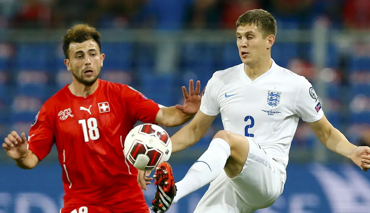 Pemain belakang Timnas Inggris, John Stones (kanan), mencoba menahan bola yang mengarah ke penyerang Swiss, Admir Mehmedi, di kualifikasi Euro 2016 di Stadion St Jakob-Park, Basel , (9/9/2014). (REUTERS/Denis Balibouse)