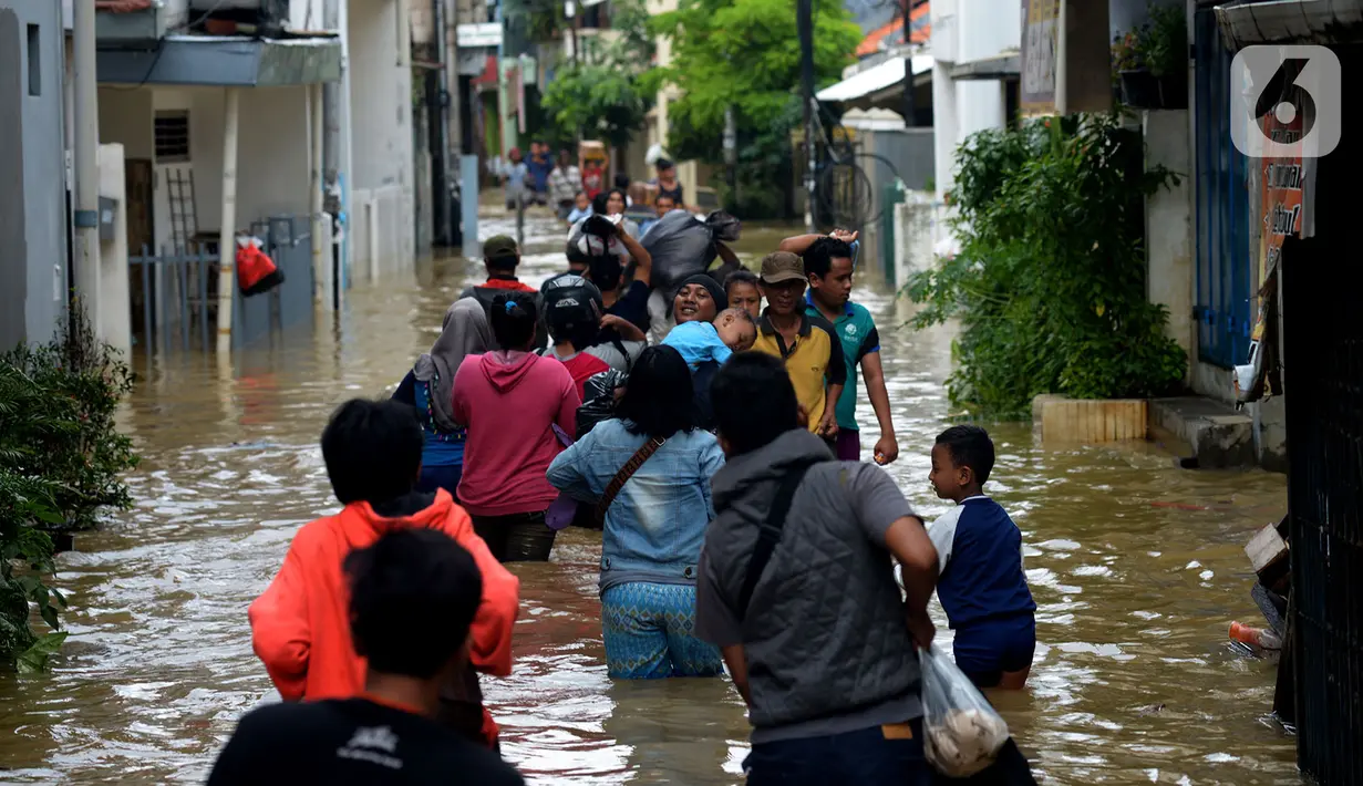 Warga melewati banjir yang menggenangi kawasan Kampung Pulo, Jakarta, Kamis (2/1/2020). Hujan yang terjadi kemarin malam membuat Kali Ciliwung meluap ke jalan. (merdeka.com/Imam Buhori)