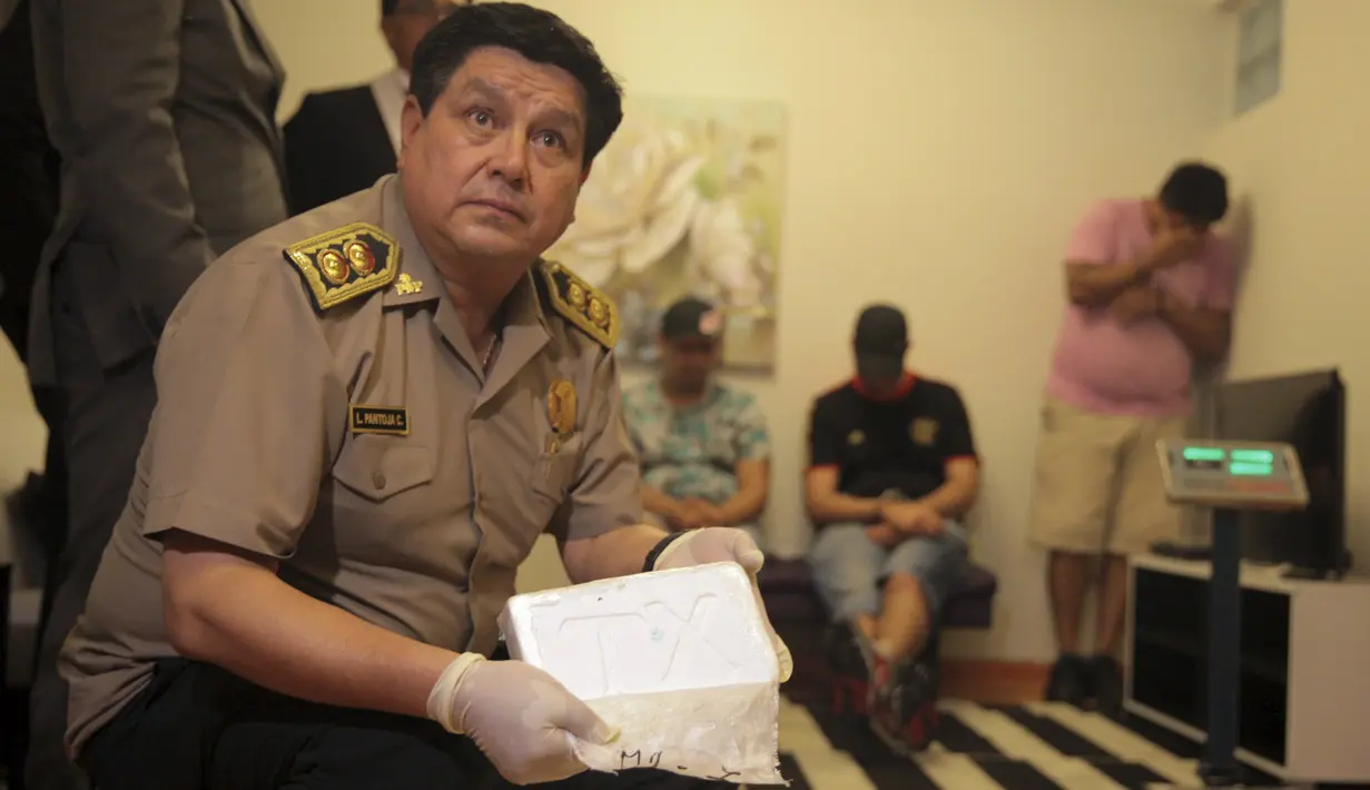Polisi menunjukkan kokain berbentuk batu bata yang berhasil diamankan di sebuah apartemen di Miraflores, Lima, Peru, Selasa (22/3). 52 batu bata kokain diamankan dari tangan tiga tersangka, dua di antaranya berasal dari Prancis. (REUTERS/Guadalupe Pardo)