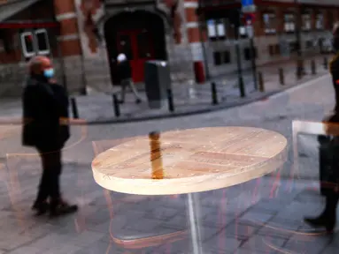 Refleksi orang-orang terlihat dari jendela depan sebuah bar yang tutup di pusat kota Brussel, Belgia, Kamis (8/10/2020). Brussels pada Rabu, 7 Oktober 2020, memutuskan menutup semua bar, ruang dansa, dan kafetaria selama sebulan sebagai upaya membendung lonjakan COVID-19. (AP Photo/Francisco Seco)