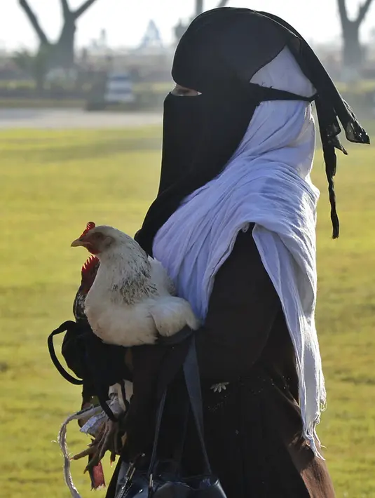 Seorang pengungsi Rohingya membawa ayam saat berjalan menaiki kapal Angkatan Laut untuk dipindahkan ke Pulau Bhasan Char di Chattogram, Bangladesh, Jumat (29/1/2021). Bangladesh mengatakan relokasi itu dilakukan secara sukarela. (AP Photo/Azim Aunon)