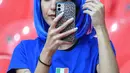 Fans wanita Italia melihat ponsel sambil merapikan rambutnya sebelum pertandingan semifinal EURO 2020 antara Italia dan Spanyol di Stadion Wembley di London (7/7/2021). (AFP/Pool/Justin Tallis)