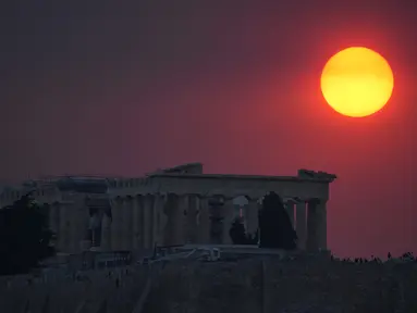 Asap dari kebakaran hutan di pinggiran ibu kota Yunani menutupi matahari saat terbenam di atas kuil Parthenon di atas Acropolis kuno di Athena, Selasa, 22 Agustus 2023. (AP Photo/Thanassis Stavrakis)