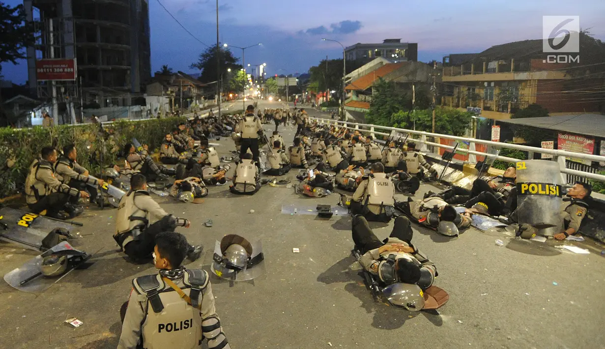 Anggota Dalmas BKO dari Polda Bali beristirahat usai mengamankan perusuh di atas fly over Slipi, Jakarta, Rabu (22/5/2019). Bentrokan panjang dengan para perusuh membuat anggota kepolisian yang berhadapan langsung kurang beristirahat. (merdeka.com/Arie Basuki)