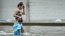 Seorang wanita dan seorang anak mengarungi jalan yang terendam banjir di kota Valenzuela, Filipina pada Rabu, 2 Agustus 2023. (AP Photo/Aaron Favila)