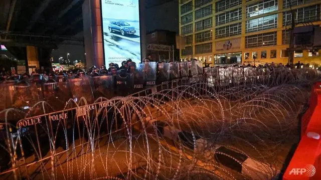 Polisi anti huru hara berjaga di belakang kawat berduri saat pengunjuk rasa berbaris selama unjuk rasa anti-pemerintah di Bangkok pada 21 Oktober 2020.