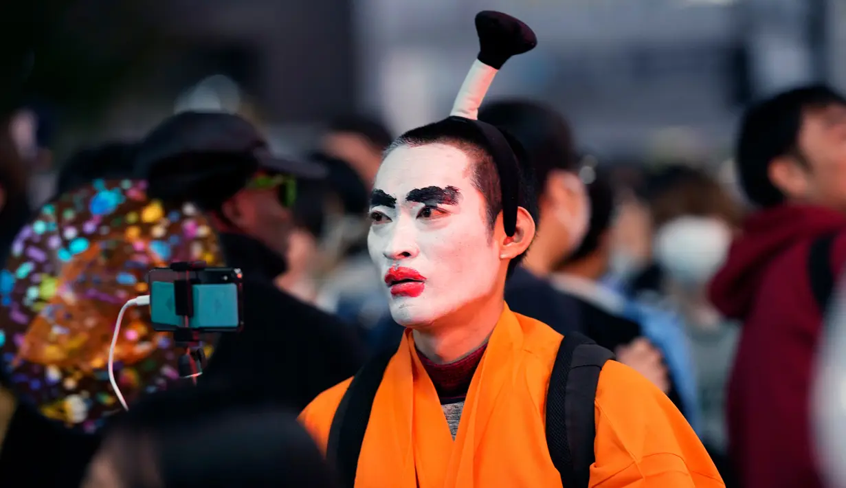 Orang-orang dengan kostum berjalan menyeberangi persimpangan jalan yang terkenal saat perayaan Halloween di distrik hiburan Shibuya, Tokyo, Jepang, 31 Oktober 2022. (AP Photo/Hiro Komae)