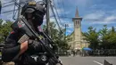 Polisi berjaga di luar gereja setelah ledakan di Makassar (28/3/2021). Berdasarkan informasi yang dihimpun di lokasi, garis polisi pun telah dibentangkan oleh petugas. Petugas masih bersiaga mengamankan lokasi. (AFP/Indra Abriyanto)