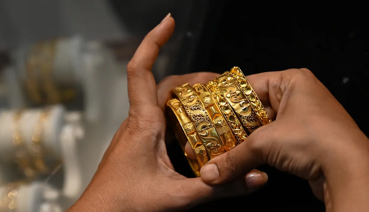Gambar diambil pada 11 Agustus 2021 menunjukkan seorang pelanggan memegang gelang emas di sebuah toko perhiasan di Mumbai, India. Putus asa mendapatkan uang tunai, banyak keluarga dan usaha kecil menjual perhiasan emas sebagai jaminan untuk mendapatkan pinjaman jangka pendek. (Punit PARANJPE/AFP)