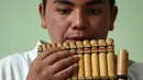 Seorang pria penduduk asli Kolombia memainkan alat musik tradisonal adat mereka saatmengikuti perayaan Hari Internasional Penduduk Asli / Masyarakat Adat di Bogota (9/8). (AFP Photo/Raul Arboleda)