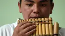 Seorang pria penduduk asli Kolombia memainkan alat musik tradisonal adat mereka saatmengikuti perayaan Hari Internasional Penduduk Asli / Masyarakat Adat di Bogota (9/8). (AFP Photo/Raul Arboleda)