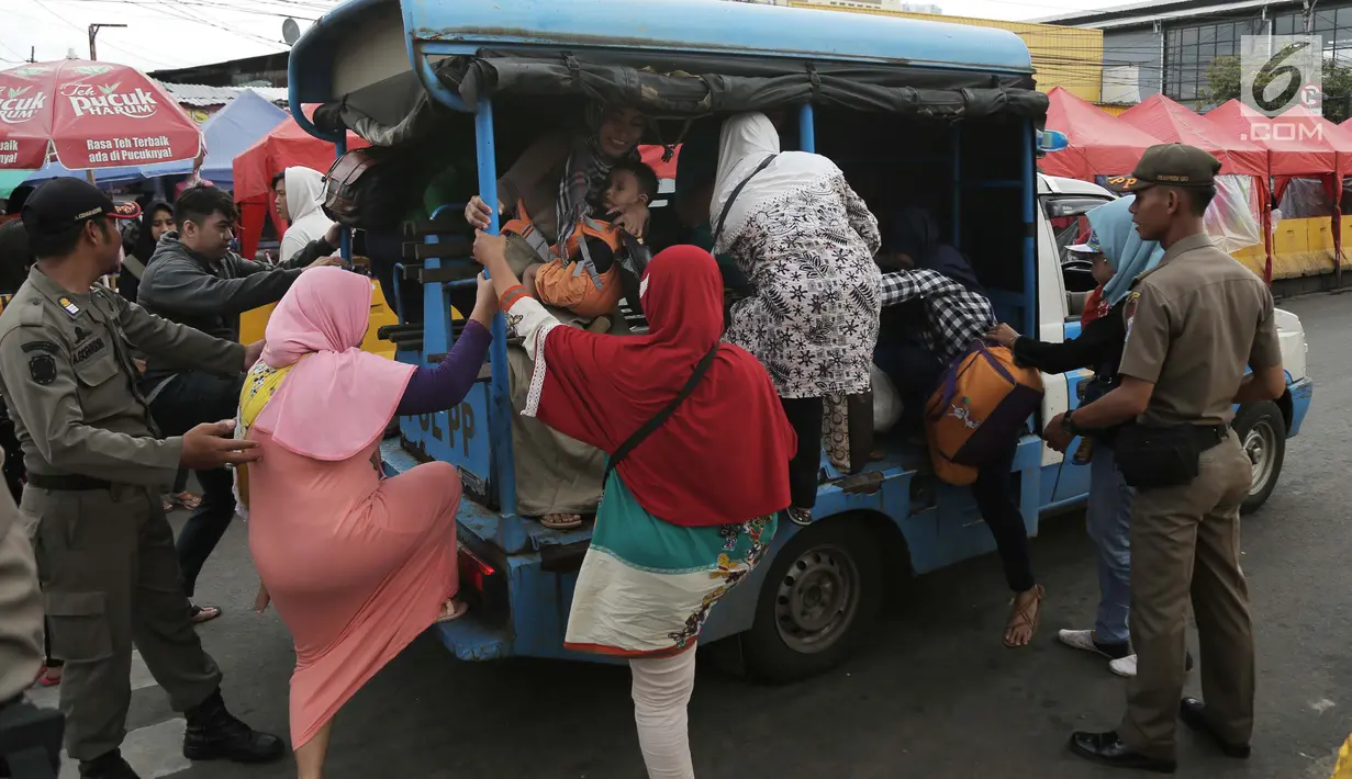 Petugas Satpol PP membantu warga menaiki mobil patroli mereka di jalan Jatibaru Raya, Jakarta, Selasa (30/1). Petugas menawarkan tumpangan kepada warga lantaran tak beroperasinya Bus TransJakarta Tanah Abang Explorer. (Liputan6.com/Gempur M Surya)