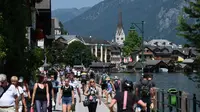 Turis mengunjungi kota Hallstatt di Danau Hallstatt dengan Gereja Injili di pusatnya, Austria Atas, pada 21 Juli 2021. (BARBARA GINDL / APA / AFP)