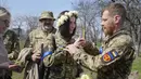 Tentara Ukraina Vyacheslav mengenakan cincin kawin pada jari Anastasia saat upacara pernikahan mereka di taman kota di Kiev, Ukraina, 7 April 2022. (AP Photo/Efrem Lukatsky)