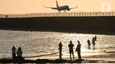 Wisatawan mengunjungi objek wisata Pantai Kelan dengan latar belakang pesawat yang mendarat di Tuban, Badung, Denpasar, Kamis (5/5/20222). Kunjungan wisatawan domestik (Wisdom) ke Pulau Bali, saat libur Lebaran Idul Fitri tahun 2022 terus meningkat. Per hari kedatangan wisdom rata-rata 40 ribu. (merdeka.com/Arie Basuki)