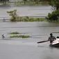 Penduduk desa mendayung perahu-perahu desa dengan barang bawaan mereka untuk pindah ke daerah-daerah yang lebih aman melalui banjir di distrik Morigaon di Assam, India (26/6/2020). (AP Photo/Anupam Nath)