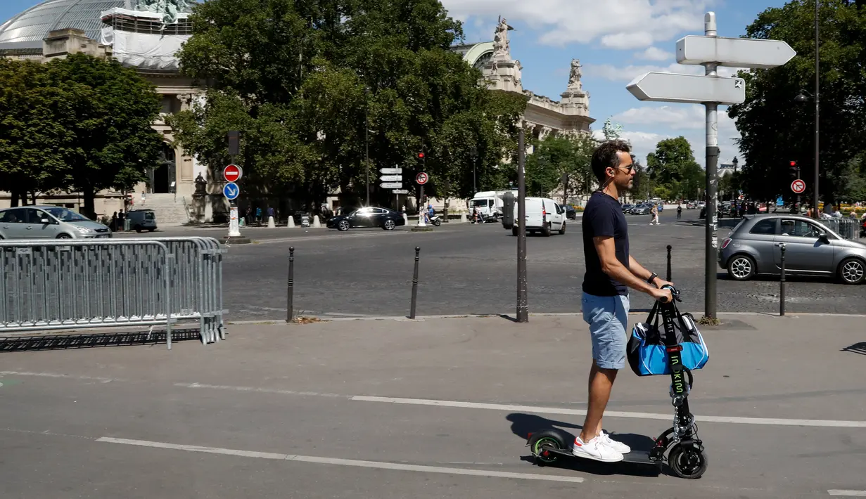 Seoarang pria menggunakan skuter listrik saat beraktivitas di Paris, Prancis (9/7). Skuter listrik ini dibuat oleh perusahaan AS Lime yang merupakan penyewaan transportasi sepeda dan skuter di berbagai kota. (AFP Photo/Francois Guillot)
