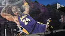 Pesepeda melintas di depan lukisan mural bintang LA Lakers, Kobe Bryant di Los Angeles, California, Selasa (26/1/2021). Lukisan dibuat untuk mengenang 1 tahun tragedi kecelakaan helikopter yang menewaskan Kobe Bryant bersama putrinya, Gianna. (Getty Images via AFP/Harry How)