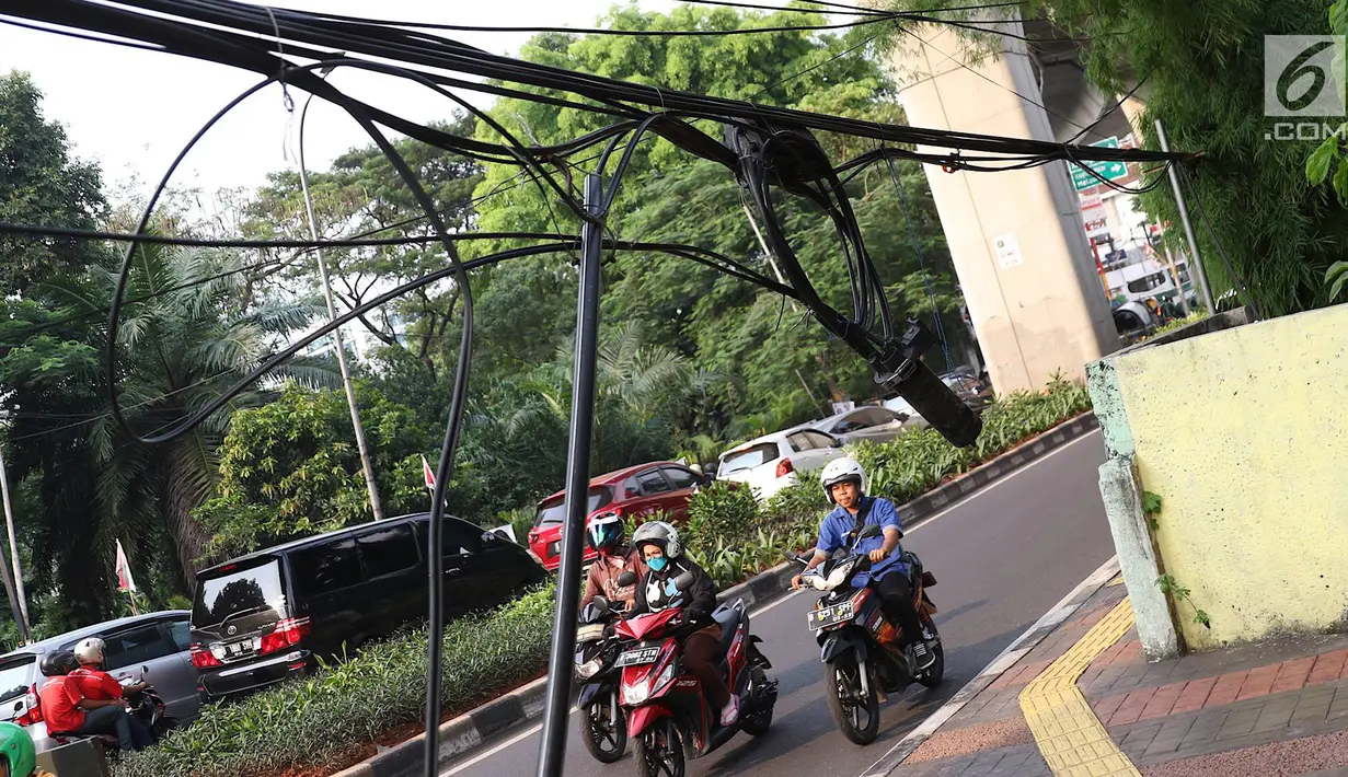 Instalasi kabel menjuntai ke trotoar di Jalan Kyai Maja, Jakarta, Rabu (10/4). Selain menganggu kenyamanan pejalan kaki, kondisi instalasi kabel yang semrawut tersebut juga berbahaya apabila mengandung aliran listrik. (Liputan6.com/Immanuel Antonius)