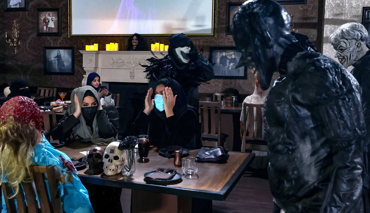 Aktor berkostum zombie memeriahkan suasana di restoran "Shadows" bertema horor di kota hiburan Boulevard, Riyadh, Arab Saudi, 19 Januari 2022. Restoran tersebut menawarkan pengalaman unik kepada pelanggan dari hidangan dengan tengkorak dan darah ditemani zombie serta vampir. (Fayez Nureldine/AFP)