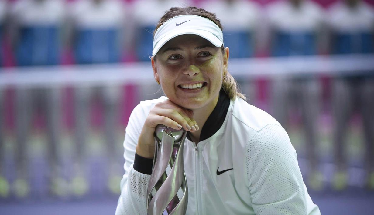 Senyum Maria Sharapova saat berpose dengan trofi setelah memenangkan pertandingan melawan Aryna Sabalenka di turnamen tenis Tianjin Open di Tianjin (15/10). Sharapova menang 7-5 7-6 atas Sabalenka. (AFP Photo/Wang Zhao)