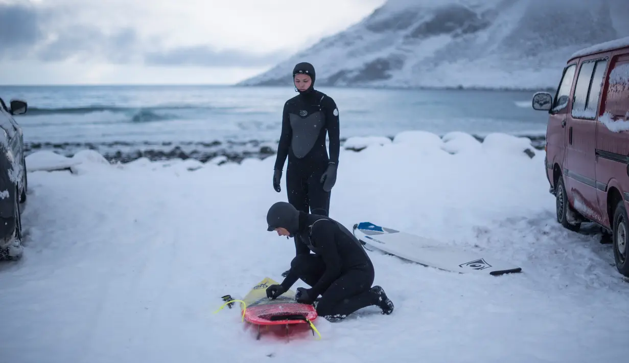 Seorang surfer mengolesi lilin di papannya sebelum berselancar di Unstad, Norwegia Utara (10/3). Peselancar ini bersiap menaklukan ombak dengan konidisi suhu minus 13 derajat Celsius. (AFP Photo/Olivier Morin)