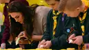 Kate Middleton membuat kue Pramuka bersama sejumlah anak-anak dalam acara Cub Scout Pack di Kings Lynn, Inggris (14/12). Dalam acara ini Kate Middleton bertemu dan bermain dengan 24 anak-anak yang ikut berpartisipasi. (Reuters/Ben Stansall/Pool)