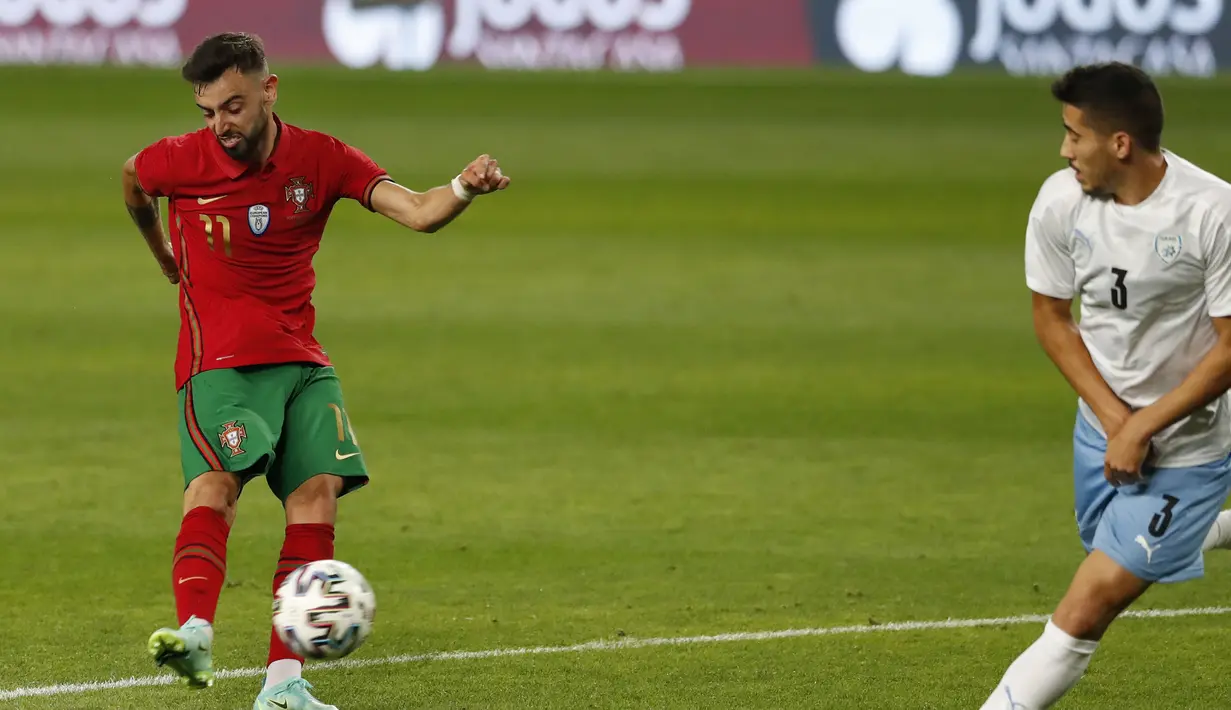 Gelandang Portugal, Bruno Fernandes (kiri) melepaskan tendangan yang berbuah gol keempat Portugal ke gawang Israel dalam laga uji coba menjelang Euro 2020 di Jose Alvalade Stadium, Lisbon, Rabu (9/6/2021). Portugal menang 4-0 atas Israel. (AP/Armando Franca)
