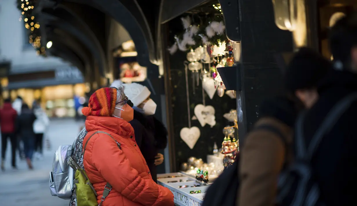 Warga memakai masker untuk melindungi diri dari virus corona saat mengunjungi pasar Natal di Wina, Austria, Rabu (17/11/2021). Warga yang tak divaksin dilarang untuk beraktivitas di Pasar Natal untuk mencegah penularan virus corona. (AP Photo/Michael Gruber)