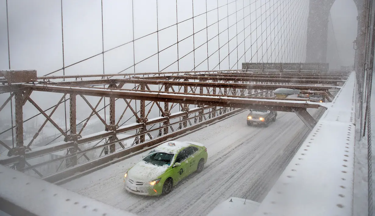 Sejumlah kendaraan melintas di jembatan Brooklyn saat badai salju New York City, AS (9/2). Badai salju akan terjadi di New York dan Philadelphia dengan kecepatan angin mencapai 48 kilometer per jam. (Drew Angerer / Getty Images / AFP)