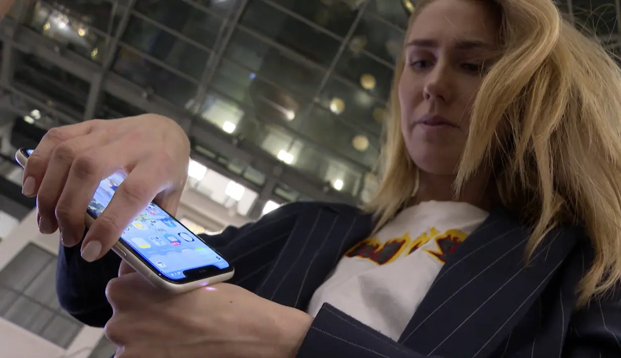 Manajer pemasaran, Amanda Back memindai dengan smartphone sebuah microchip yang dikembangkan oleh perusahaan DSruptive Subdermals dan ditanamkan di tangannya untuk mengungkapkan kartu kesehatannya di Epicenter Stockholm (20/12/2021). (AFP/Viken Kantarci)