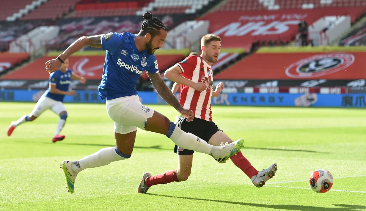 Striker Everton, Theo Walcott, berebut bola dengan bek Sheffield United, Chris Basham, pada laga lanjutan Premier League di Bramall Lane Stadium, Selasa (21/7/2020) dini hari WIB. Everton menang 1-0 atas Sheffield United. (AFP/Peter Powell/pool)