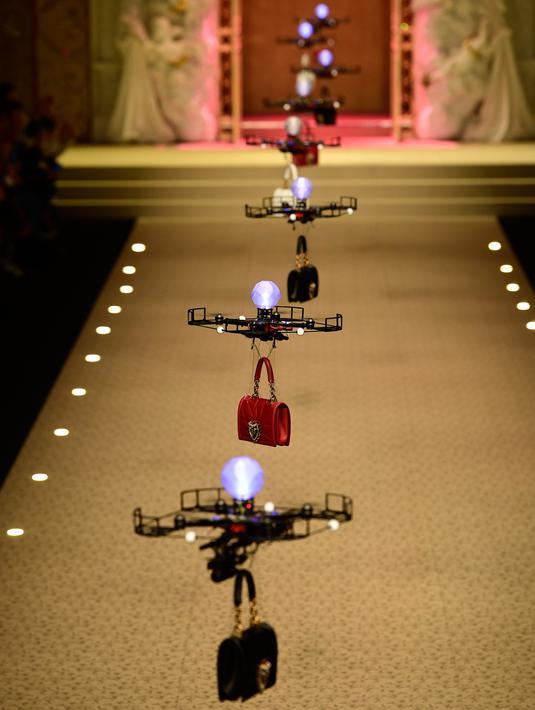 Barisan pesawat tanpa awak (drone) membawa koleksi tas tangan Dolce & Gabbana pada Milan Fashion Week 2018, Minggu (25/). Bak model, deretan drone terbang berbaris rapi diiringi soundtrack 'Black Panther', 'All of the Stars'. (AP/Antonio Calanni)