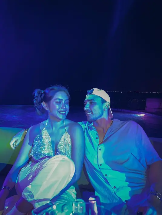 Dalam beberapa foto, Jessica Iskandar berpose di samping sang suami. Ia mengenakan cropped top halter-neck. Cropped top ini memiliki aksen metalik yang edgy. Foto: Instagram.