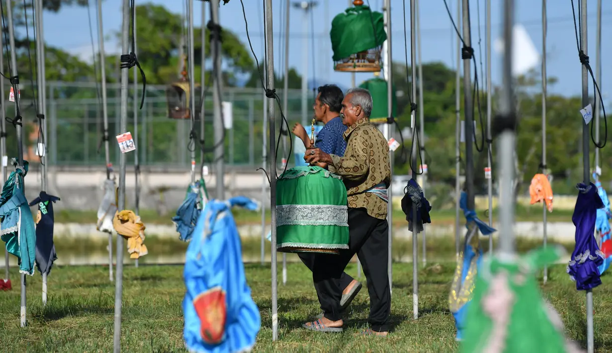 Seorang pria membawa seekor burung dalam sangkar saat kompetisi nyanyian burung di Narathiwat, Thailand, Rabu (21/9/2022). Sekitar 1.500 burung dari Thailand, Malaysia dan Singapura diikutsertakan dalam kontes tahuna ini. (Madaree THOLALA / AFP)
