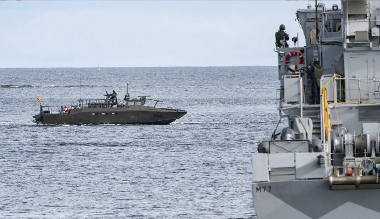Sebuah 'kapal musuh' dalam bentuk kapal Swedia "Stridsbat 90" (kiri) terlihat di depan kapal penyapu ranjau HMS Ulvon saat latihan ranjau di luar Vastervik, Swedia, 21 September 2021. Latihan ini melibatkan sekitar 2.000 orang dan sekitar 30 kapal dari 13 negara. (JOHAN NILSSON/TT NEWS AGENCY/AFP)