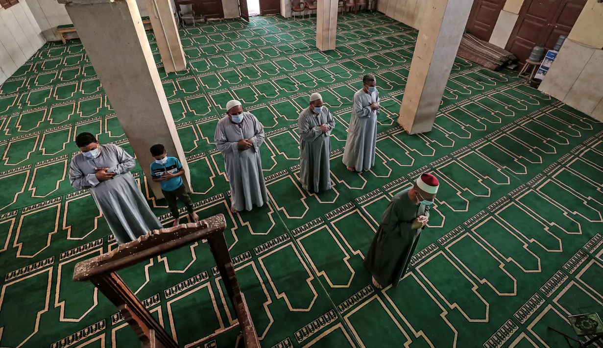 Imam memimpin Umat Muslim, yang mengenakan masker karena pandemi Covid-19, selama salat Idul Fitri di dalam sebuah masjid di desa Shamma, provinsi Nou delta, Menoufia di Mesir pada 24 Mei 2020. (Photo by Mohamed el-Shahed / AFP)