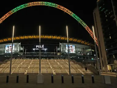 Lengkungan Stadion Wembley menyala dalam warna Brasil dan layar menampilkan gambar Pele setelah pengumuman bahwa mantan pemain sepak bola Brasil itu meninggal dunia, London, Inggris, 29 Desember 2022. Edson Arantes do Nascimento atau yang dikenal sebagai Pele, raja sepak bola Brasil yang menang rekor tiga Piala Dunia dan menjadi salah satu tokoh olahraga paling berwibawa abad lalu, meninggal pada usai 82 tahun di di Sao Paulo. (Kieran Cleeves/PA via AP)
